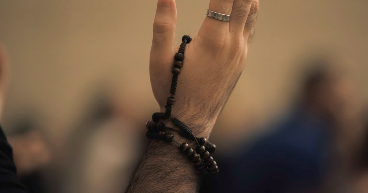 Hands raised in supplication holding prayer beads